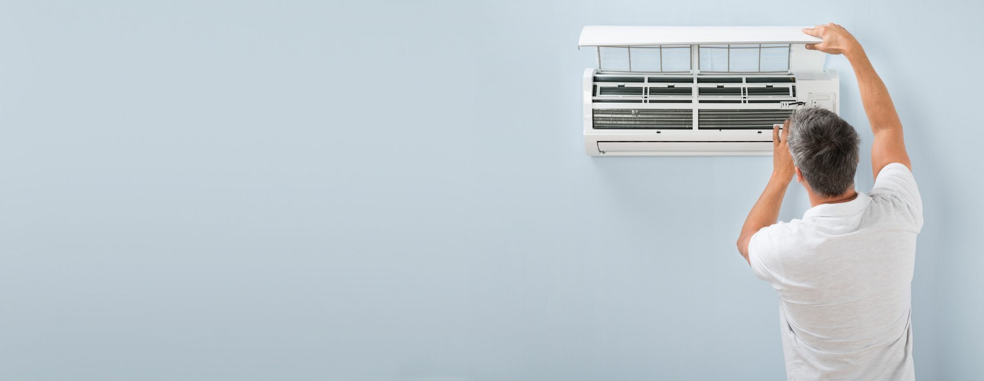 Rear View Of A Man Cleaning Air Conditioning System